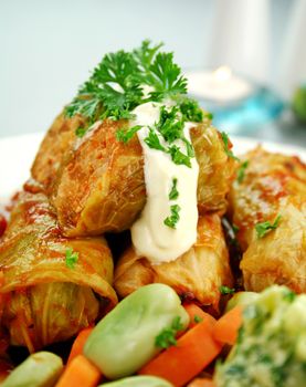 Baked pork and cabbage rolls with carrots and broad beans with a tomato sauce.