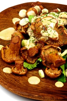 Delicious Roasted Edible Chanterelles with Cheese Sauce and Greens on Wooden Plate