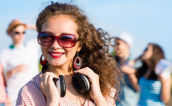 young woman with headphones on a background of blue sky and funny friends