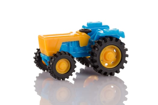 Small plastic tractor toy isolated on white background close up.