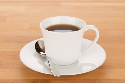 Cup of coffee and silver spoon on wooden table close up.