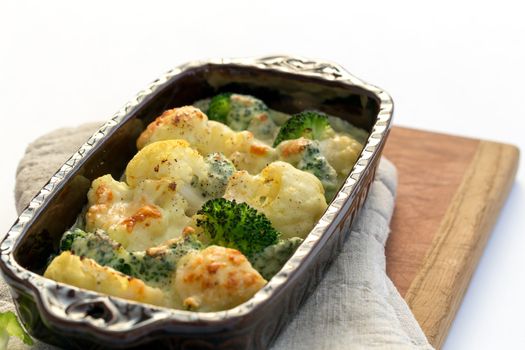 Gratin of cauliflower, broccoli and cheese in brown rustic dish.