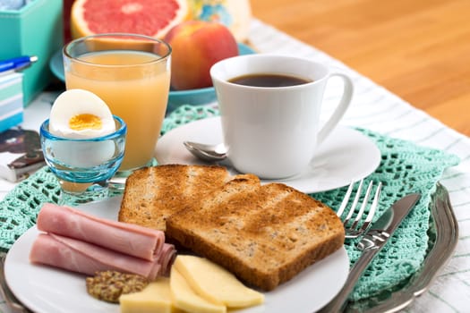 Breakfast with toast, ham, cheese, egg, grapefruit, juice and cup of coffee.