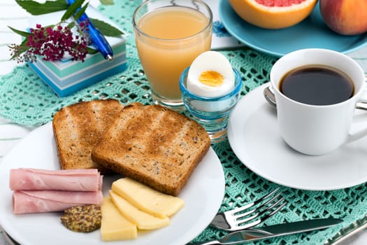 Breakfast with toast, ham, cheese, egg, grapefruit, juice and cup of coffee.