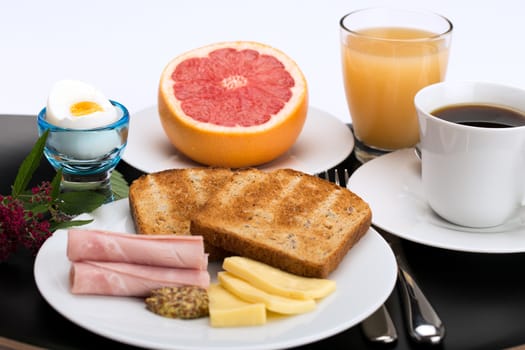 Breakfast with toast, ham, cheese, egg, grapefruit, juice and cup of coffee.