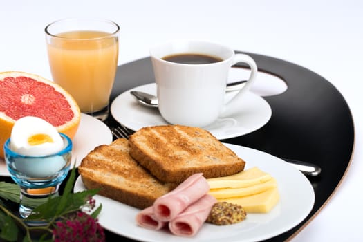 Breakfast with toast, ham, cheese, egg, grapefruit, juice and cup of coffee.