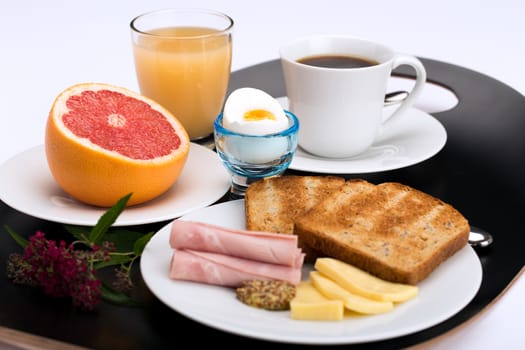 Breakfast with toast, ham, cheese, egg, grapefruit, juice and cup of coffee.