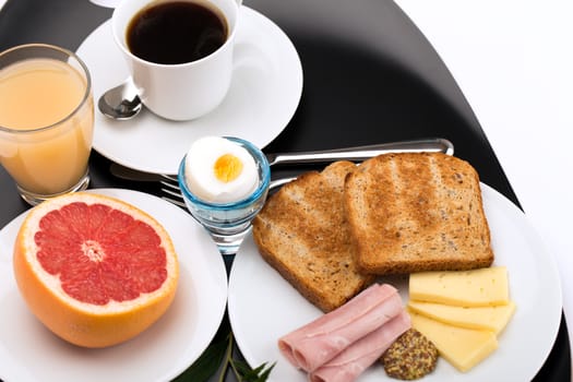 Breakfast with toast, ham, cheese, egg, grapefruit, juice and cup of coffee.