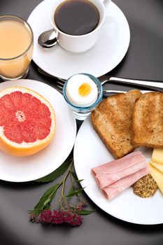 Breakfast with toast, ham, cheese, egg, grapefruit, juice and cup of coffee.