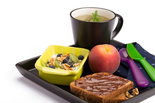 Healthy breakfast with chocolate bread, muesli, peach and cup of tea.