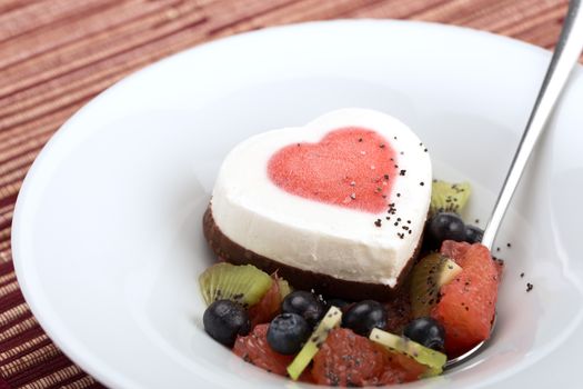 Heart ice cream with blueberry, grapefruit and kiwi on white plate.