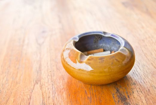 An ashtray filled with smoked cigarettes on a wooden table