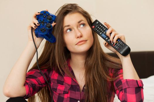 Young woman can't choose between TV console and joystick