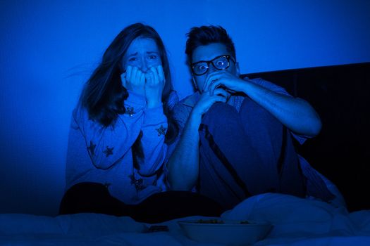 Caucasian couple watching scary movie at home