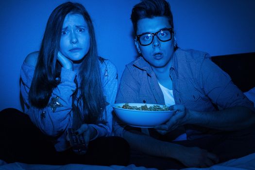 Caucasian couple watching scary movie at home