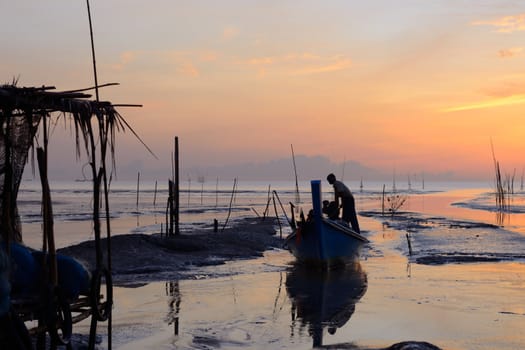 Fisherman is standing on fishing boat with sunrise background at thailand