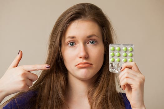 Sad caucasian woman holding pills in hand