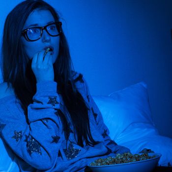 Young woman watching scary movie at home darkness