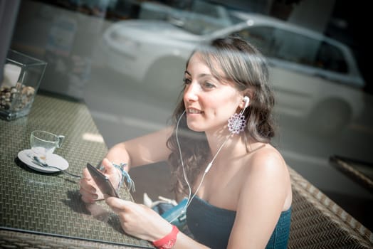 young beautiful woman listening to music at the coffee
