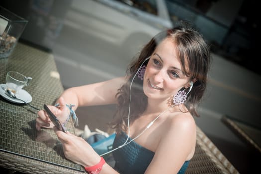 young beautiful woman listening to music at the coffee