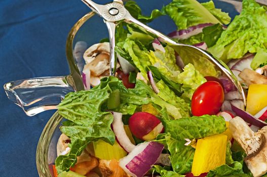 Salad in glass bowl with tongs
