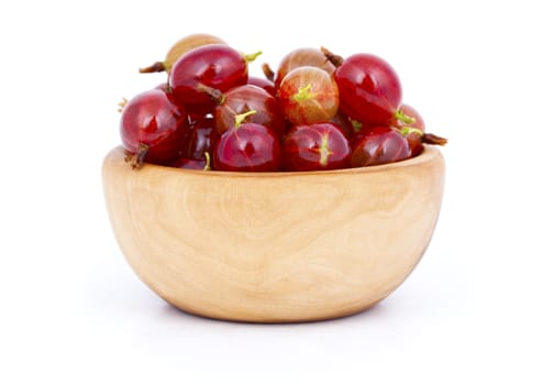 fresh red gooseberries in a wooden bowl, over a white background.