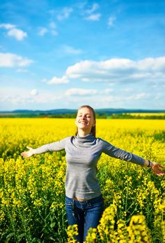 Girl with outstretched arms at colza field