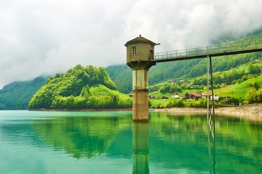 Beautiful emerald mountain lake in Switzerland under low clouds