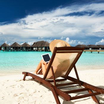 Young woman in hat with tablet pc at the beach