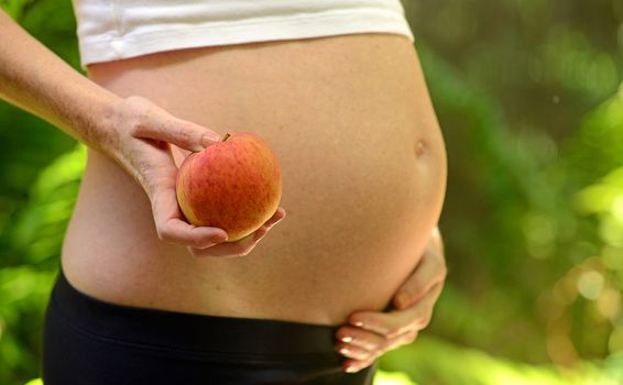 pregnant woman holding apple to signify healthy eating and nutrition during pregnancy