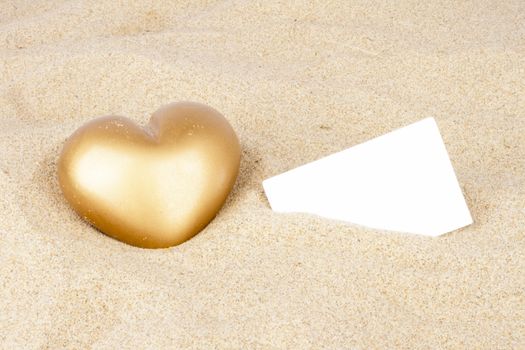 Golden heart in the sand with business card