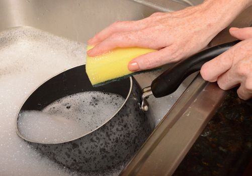 scrubbing a pot in soapy water to do dishes