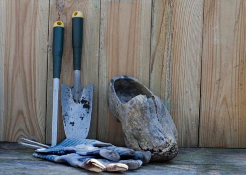 garden tools gloves and wooden shoe on a wooden shelf