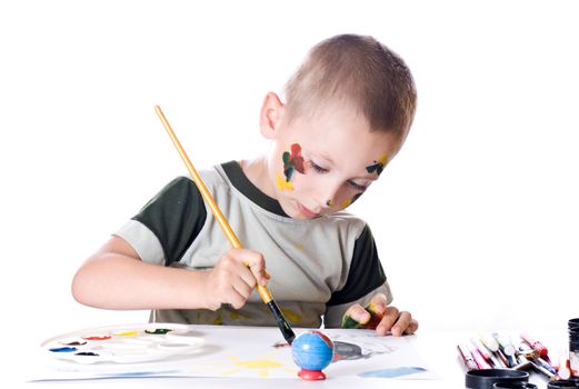 Boy paints watercolors paints on a sheet of paper