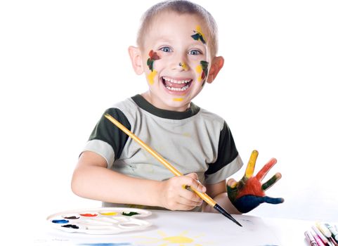 Boy paints watercolors paints on a sheet of paper