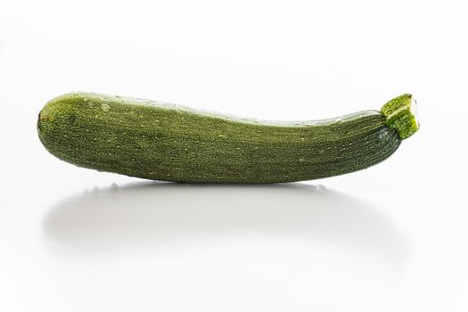 Fresh courgette with water drops over a white background.