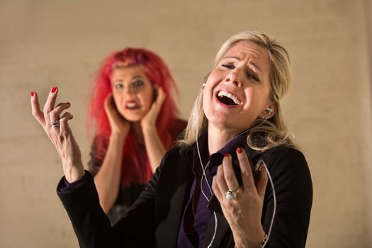 Happy woman singing loudly with annoyed teenager nearby