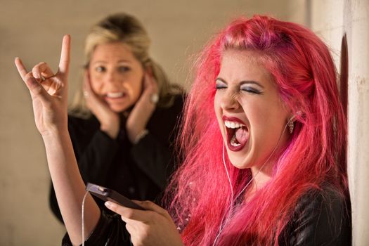 Woman covering ears while teenage girl sings