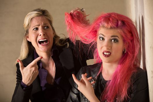 Shocked blond woman holding pink hairdo of teenager