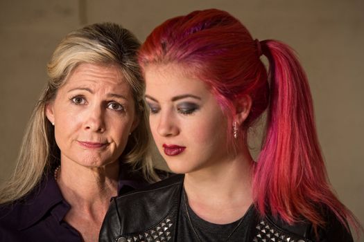 Mature woman with teenage girl in pink hair looking down