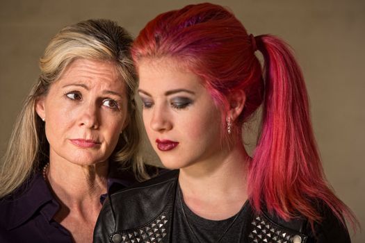 Teenage girl looking down with sympathetic woman next to her