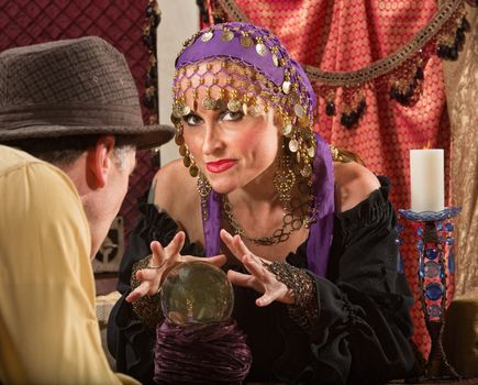 Sexy fortune teller waving hands over crystal ball