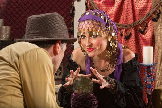 Grinning European fortune teller with hands over crystal ball