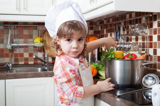 Little girl plays the cook and makes a dinner