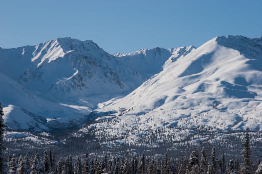 Winter mountains rise sharply above the landscape of Interior, Alaska