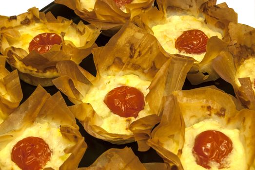 Small homemade pies with cheese and cherry tomato in a basket of pastry