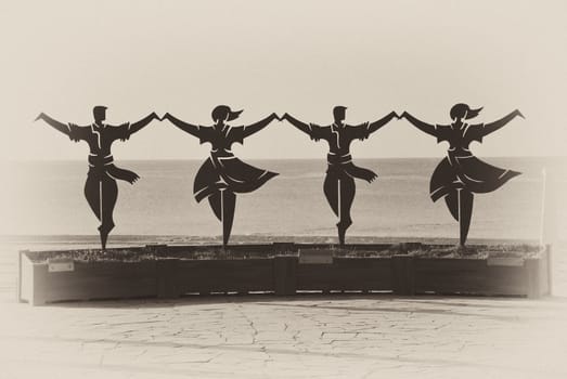 Statue of Catalonian dancers with the sea in background, in sepia