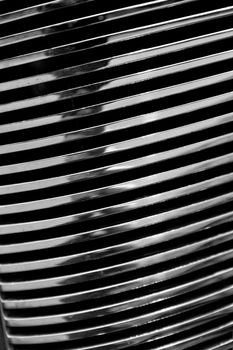 Black and white close up view of a chrome automotive grill on an antique classic car. 