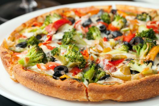 A fresh medium size specialty pizza with extra toppings hot and fresh out of the oven. Shallow depth of field.