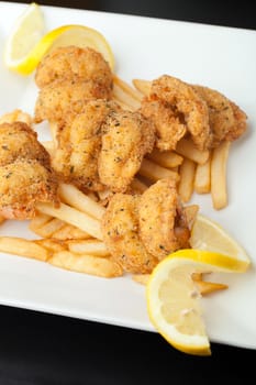 Fried shrimp and french fries plate garnished with lemon.